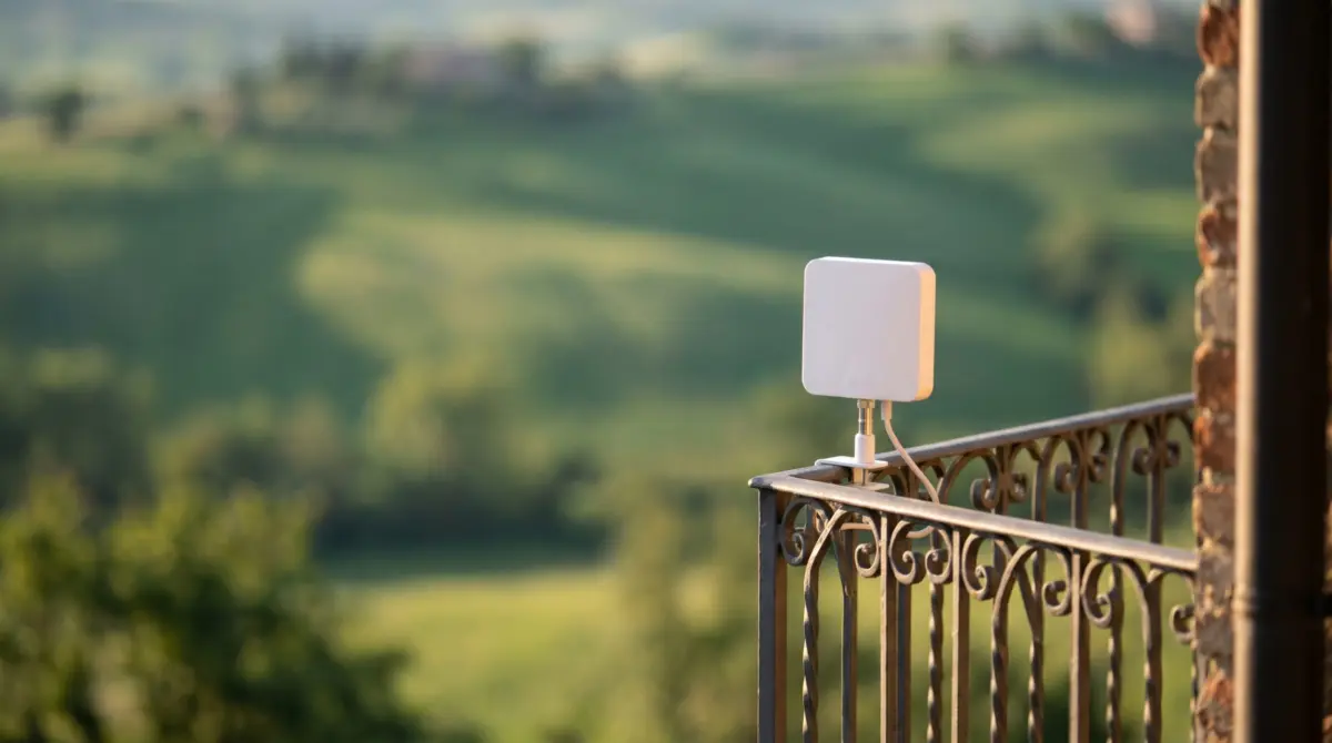Piccola antenna Ari@net installata sulla ringhiera di un balcone con vista sulle colline
